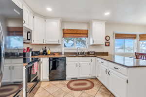 Kitchen with dark stone counters, a sink, black appliances, recessed lighting, and a peninsula