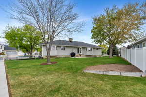 Rear view of house featuring a lawn, a patio, and fence
