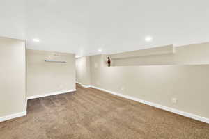 Finished below grade area with baseboards, visible vents, carpet floors, and recessed lighting