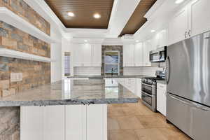 Kitchen with tasteful backsplash, a sink, a tray ceiling, stainless steel appliances, and a peninsula