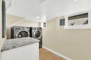 Clothes washing area featuring washing machine and dryer, baseboards, recessed lighting, and laundry area