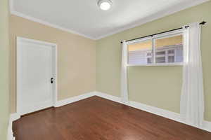 Unfurnished room with baseboards, crown molding, and dark wood-style floors