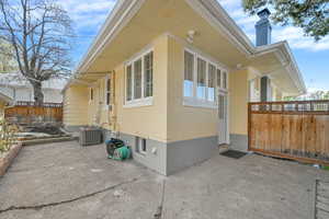 View of property exterior with fence, a chimney, cooling unit, and a patio
