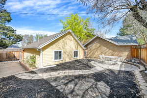View of side of property featuring a fenced backyard, a patio area, and a shingled roof
