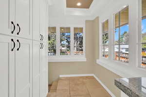Mudroom with a raised ceiling, baseboards, recessed lighting, crown molding, and light tile patterned floors