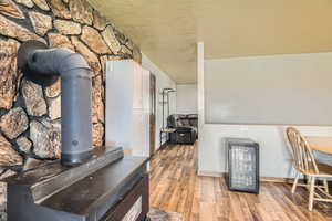 Interior space with wood finished floors, a textured ceiling, beverage cooler, a wood stove, and baseboards