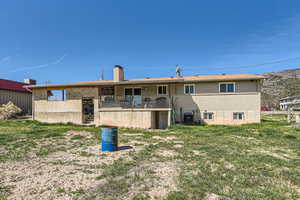 Back of property with a lawn, central AC, and a chimney