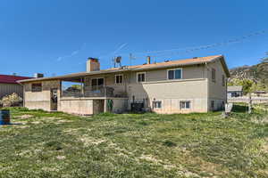 Back of house with a chimney, a yard, and central AC unit
