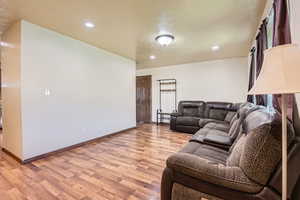 Living room with baseboards, light wood finished floors, and recessed lighting