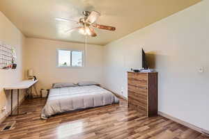 Bedroom featuring wood finished floors, visible vents, baseboards, and ceiling fan
