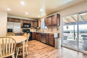 Kitchen with decorative backsplash, light wood-style flooring, light countertops, and black appliances