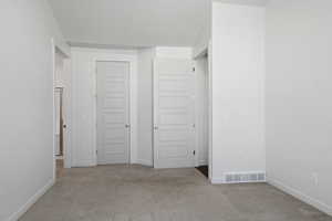 Unfurnished bedroom featuring baseboards, carpet flooring, and visible vents