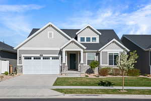 Craftsman house with stone siding, driveway, and a front yard