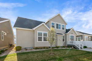 View of front facade with stucco siding, fence, a front yard, and central AC unit