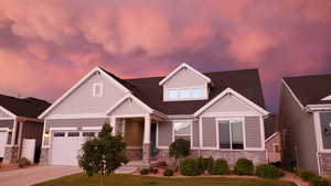 Craftsman house with concrete driveway, a porch, stone siding, and a garage