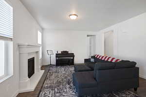 Living area featuring baseboards, dark wood-style flooring, and a fireplace with raised hearth