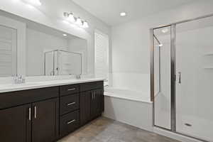 Full bathroom featuring double vanity, a shower stall, a garden tub, and a sink