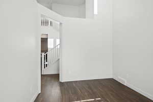 Spare room featuring baseboards, dark wood-style flooring, stairs, and visible vents
