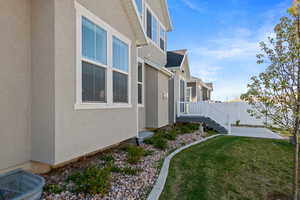 View of home's exterior with fence, a lawn, and stucco siding