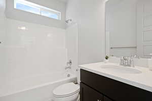 Bathroom featuring toilet, vanity, and  shower combination