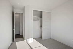 Unfurnished bedroom with light carpet, baseboards, and a closet