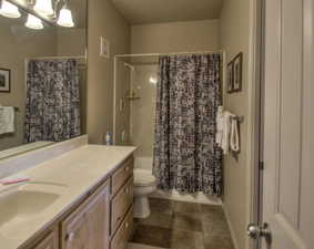 Full bathroom with vanity, shower / tub combo with curtain, toilet, a notable chandelier, and tile patterned flooring