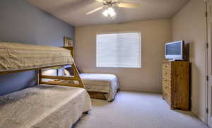 Carpeted bedroom with ceiling fan and baseboards