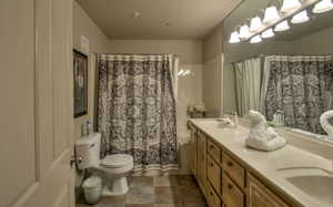 Bathroom featuring toilet, tile patterned flooring, a sink, and double vanity