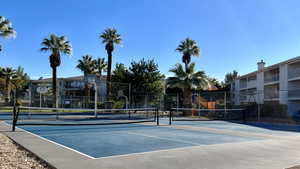 View of tennis court featuring community basketball court and fence