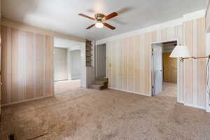 Interior space with baseboards, a ceiling fan, stairs, and wallpapered walls