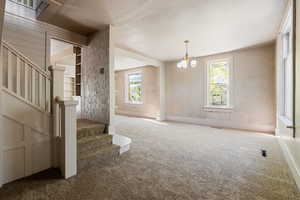 Interior space featuring stairway, visible vents, carpet flooring, and an inviting chandelier