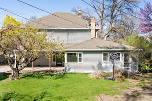 Back of property with a patio area, a lawn, a chimney, and roof with shingles