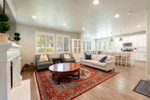 Great room featuring a fireplace, light upgraded flooring, a textured ceiling, and recessed lighting