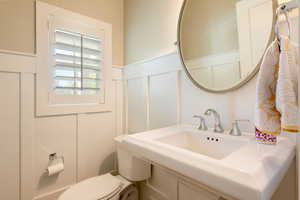 Half bathroom with a decorative, wainscoted wall, and toilet off main floor