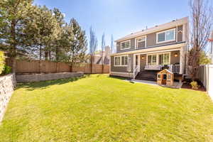 Back of property featuring a lawn, a fenced backyard, and a deck