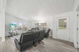 Living area featuring an inviting chandelier, lofted ceiling, wood finished floors, and baseboards