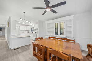 Dining room with ceiling fan, lofted ceiling, light wood-style floors, and visible vents