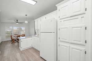 Kitchen featuring a peninsula, white cabinetry, light wood-type flooring, and freestanding refrigerator