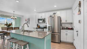 Kitchen with a kitchen breakfast bar, an island with sink, stainless steel appliances, light wood finished floors, and a sink