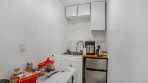 Kitchen with freestanding refrigerator, white cabinets, a sink, light countertops, and decorative backsplash