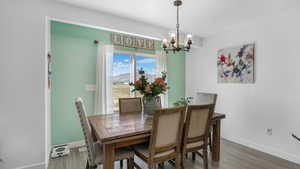 Dining room featuring baseboards, an inviting chandelier, and wood finished floors