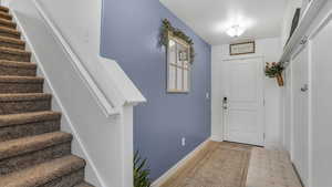 Entryway with wood finished floors, baseboards, and stairs