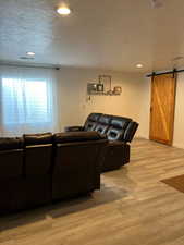 Living area with a barn door, light wood-style floors, baseboards, and recessed lighting