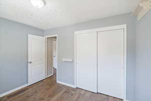 Unfurnished bedroom with baseboards, wood finished floors, and a closet