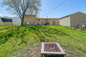 Back of house featuring a fenced backyard, a mountain view, a gate, a lawn, and an outdoor fire pit