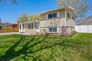 Back of house featuring a fenced backyard, central AC unit, entry steps, a lawn, and a patio