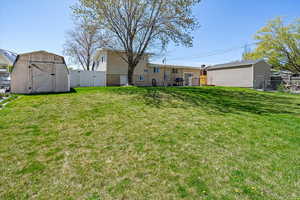 View of yard featuring a gate, a storage unit, fence, and an outdoor structure