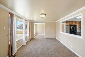 Unfurnished room featuring baseboards, crown molding, and light colored carpet