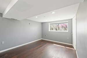 Empty room with hardwood / wood-style flooring, baseboards, visible vents, and recessed lighting