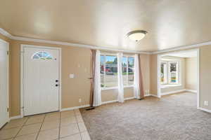 Entrance foyer with baseboards, visible vents, and ornamental molding